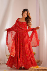 Woman wearing a red traditional outfit with a matching dupatta in a softly lit room.
