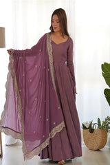 Woman wearing a long purple dress with a matching dupatta in a bright room.
