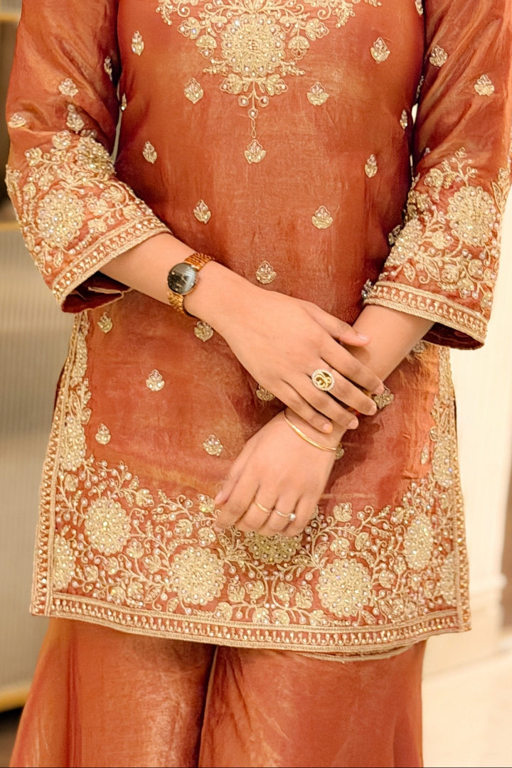 Orange traditional outfit with intricate gold embroidery on a neutral background