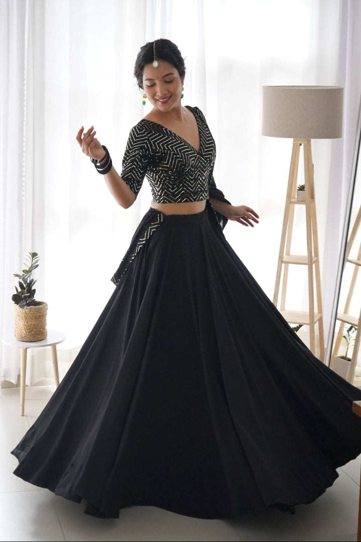 Woman in a black and white traditional outfit with a flowing skirt in a bright room.