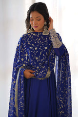 Woman wearing a blue traditional outfit with floral patterns against a white background