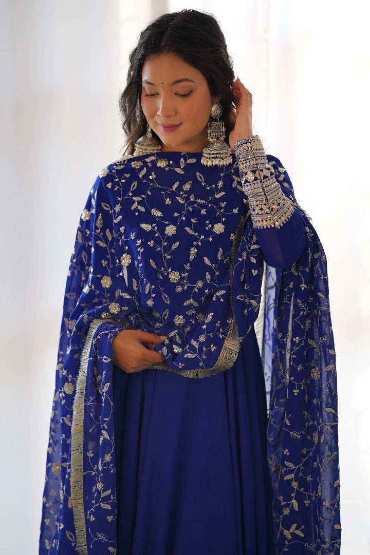 Woman wearing a blue traditional outfit with floral patterns against a white background