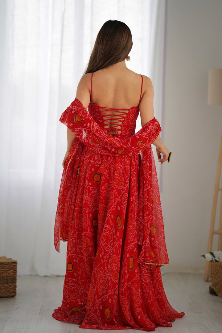 Woman wearing a red patterned dress with sheer sleeves in a minimal indoor setting.