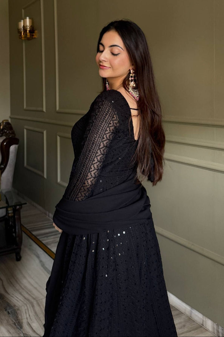 Woman wearing a black lace dress with a plain wall background