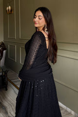 Woman wearing a black lace dress with a plain wall background