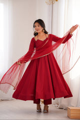 Woman in a red traditional outfit with a flowing dupatta against a white curtain background