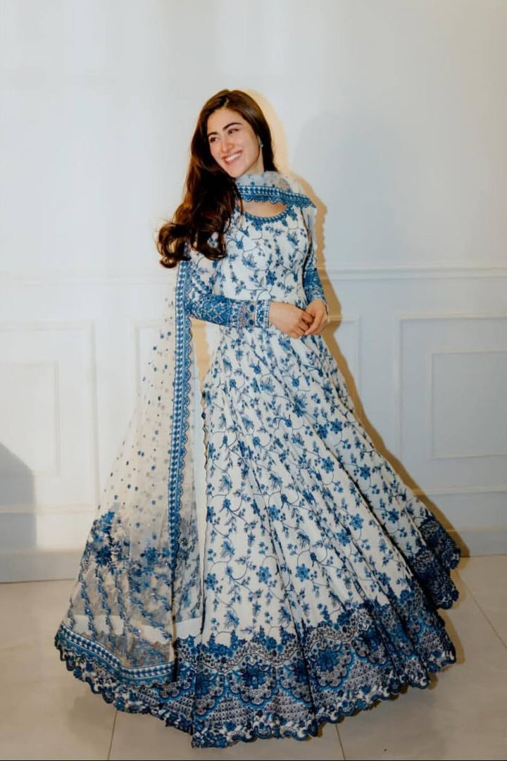 Woman wearing a white and blue floral traditional outfit with a matching dupatta.