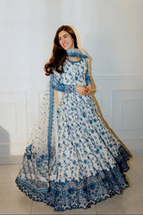 Woman wearing a white and blue floral traditional outfit with a matching dupatta.