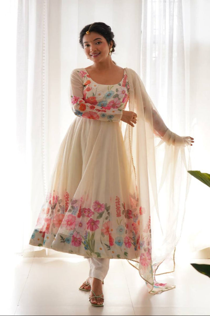 Woman wearing a floral dress with a sheer dupatta in a bright room.