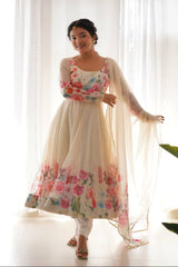 Woman wearing a floral dress with a sheer dupatta in a bright room.