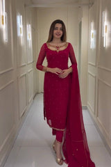 Woman in a red traditional outfit standing in a hallway.