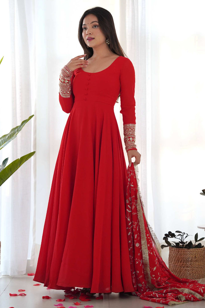 Woman wearing a red dress with a matching dupatta in a bright room.