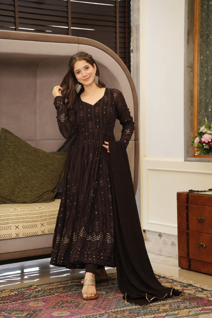 Woman in a black traditional outfit standing in a room with a bed and dresser.