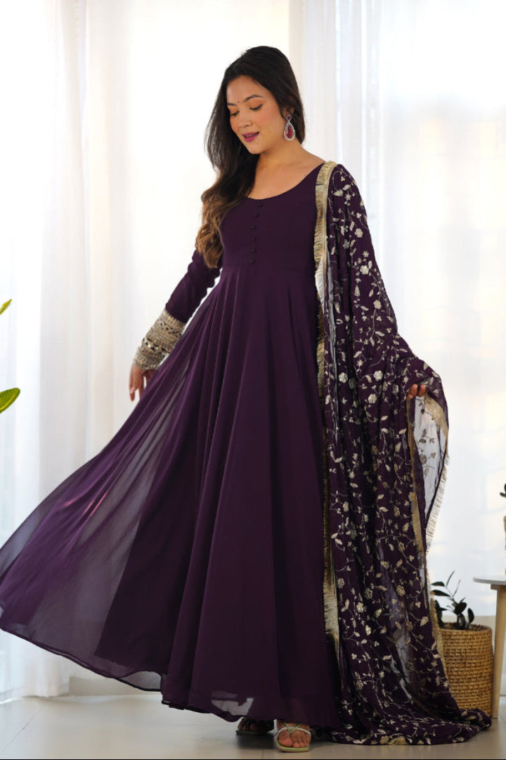 Woman wearing a long purple dress with a matching dupatta in a bright room.