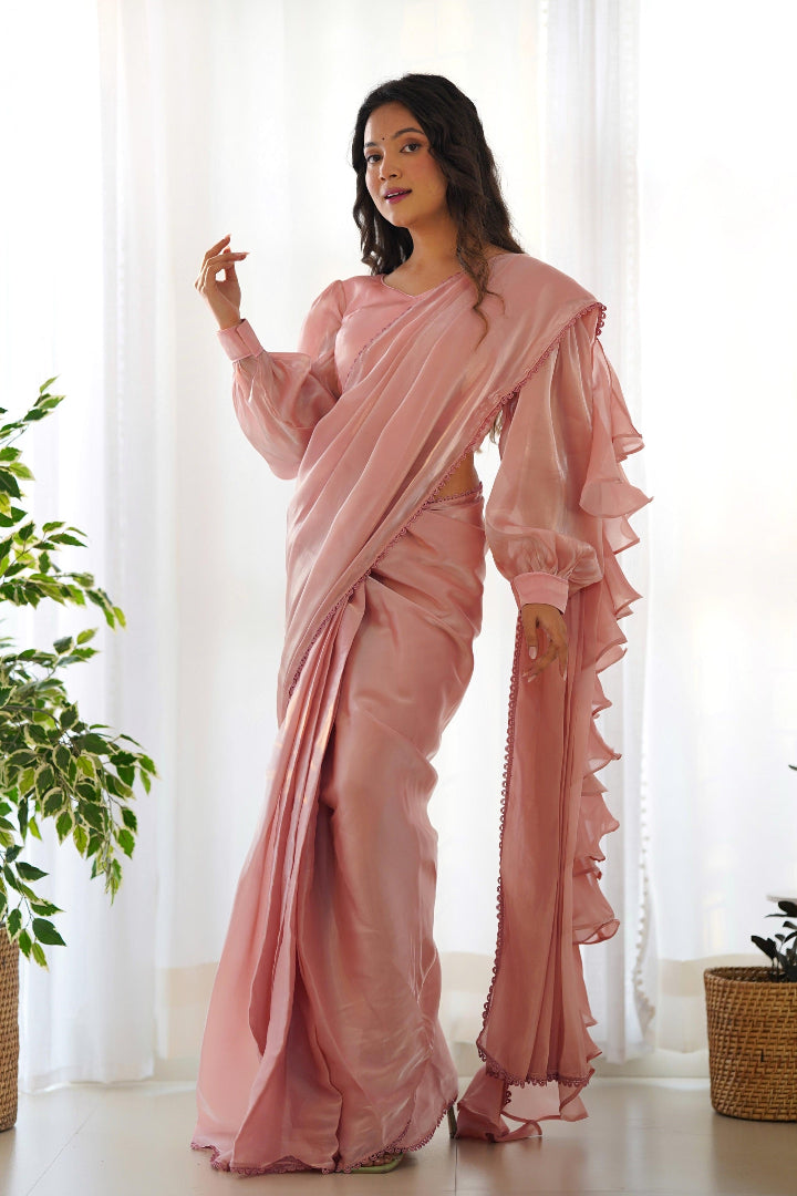 Woman wearing a pink saree with a white curtain background