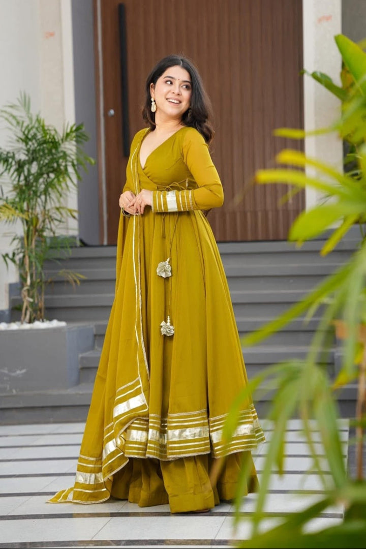 Woman in a yellow traditional outfit standing on steps with plants around