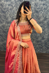 Person wearing a traditional pink saree with intricate designs against a textured wall.
