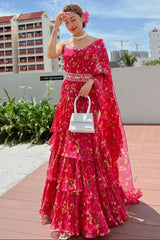 Woman in a red floral dress standing outdoors with buildings in the background