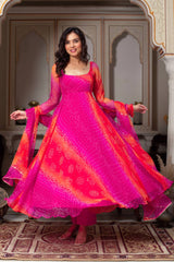 Woman in a vibrant pink and orange traditional outfit standing in an ornate room.
