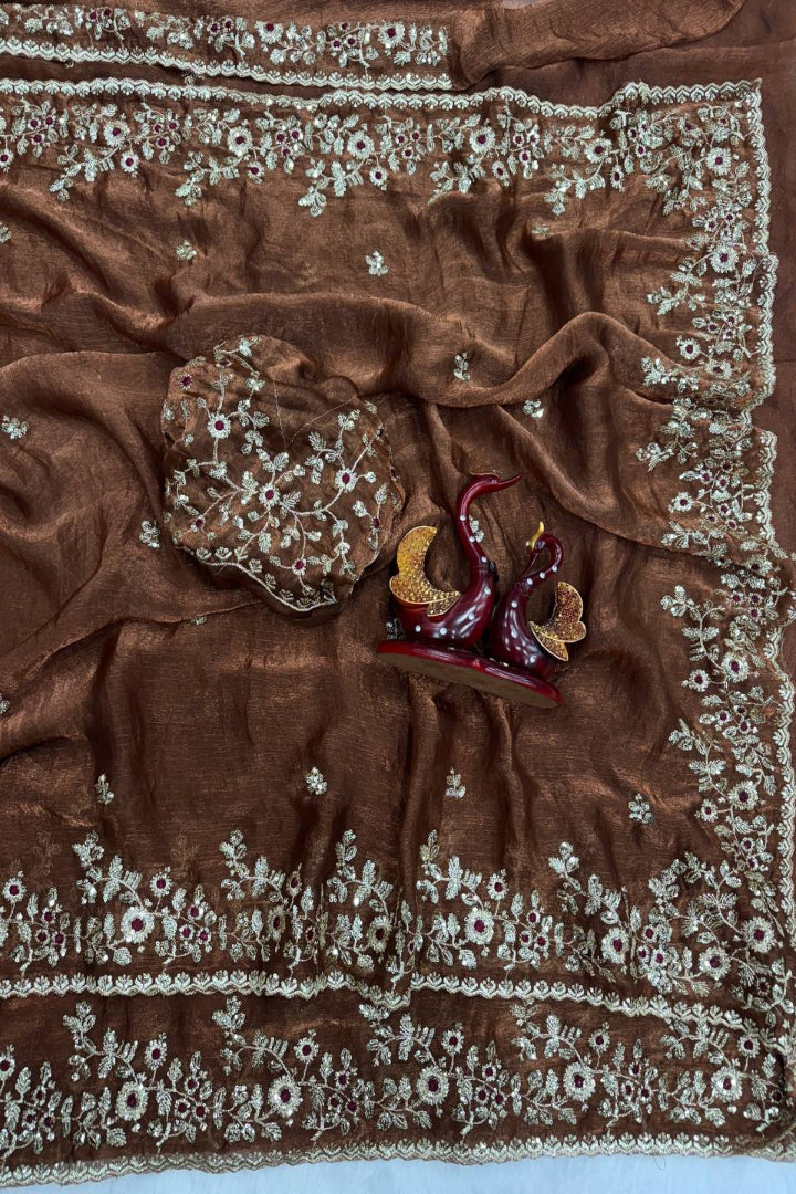 Brown fabric with intricate white embroidery on a light blue background