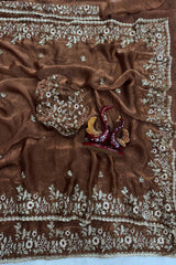 Brown fabric with intricate white embroidery on a light blue background