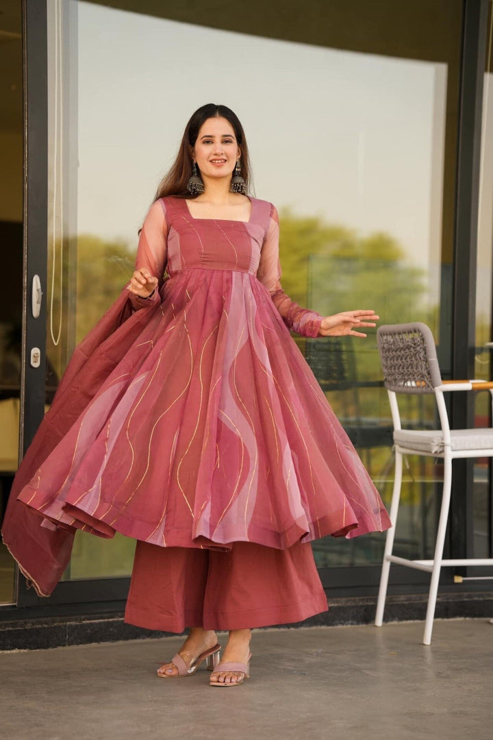 Woman in a maroon traditional outfit standing in front of a glass door.
