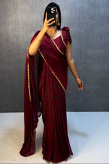 Person wearing a maroon saree with gold border against a plain background