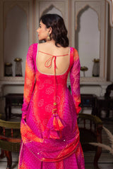 Woman wearing a vibrant pink and orange traditional outfit with intricate patterns in an indoor setting.