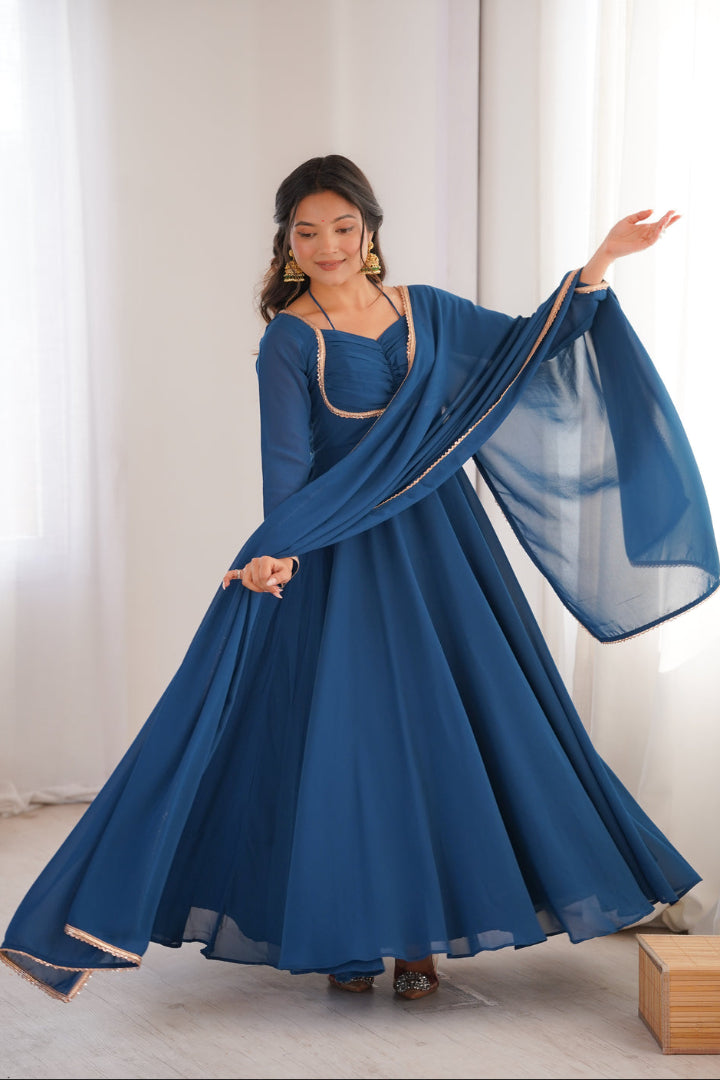 Woman wearing a blue traditional outfit with a matching shawl in a bright room.