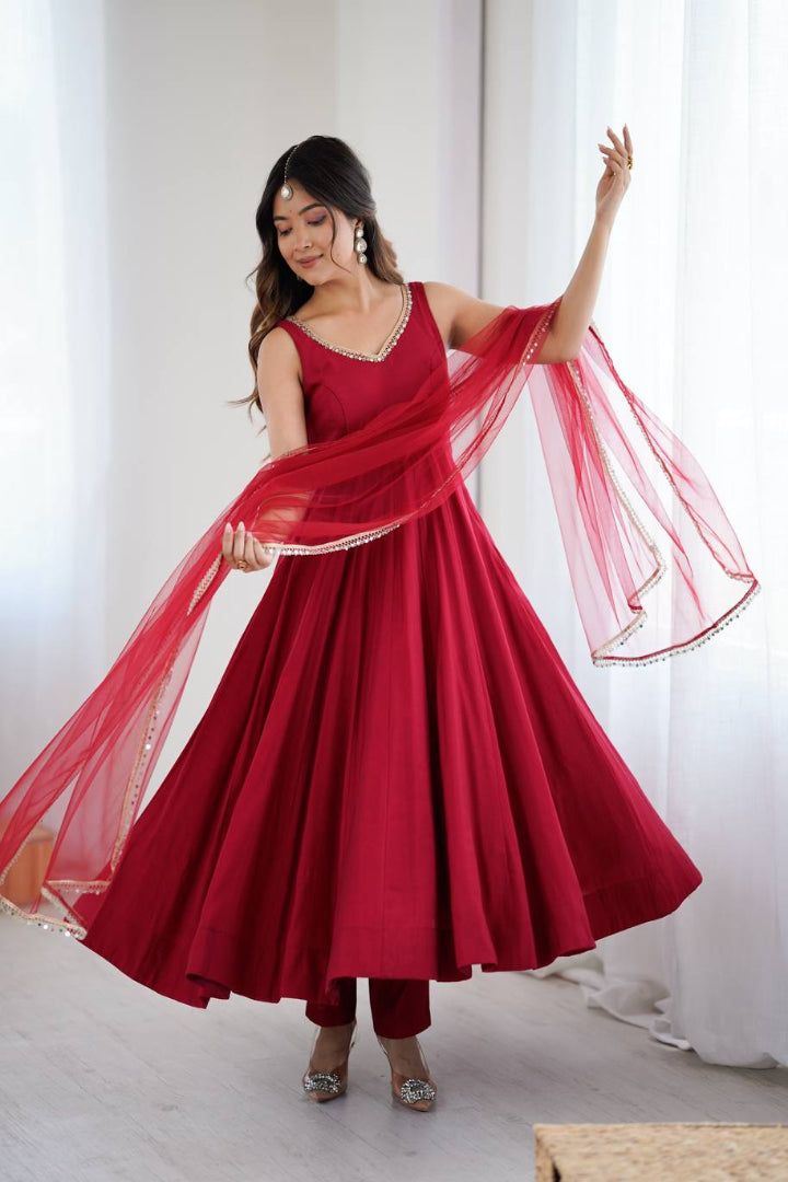 Woman in a red traditional outfit with a flowing fabric against a white curtain background
