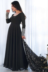 Woman in a long black dress with a flowing train against a white background