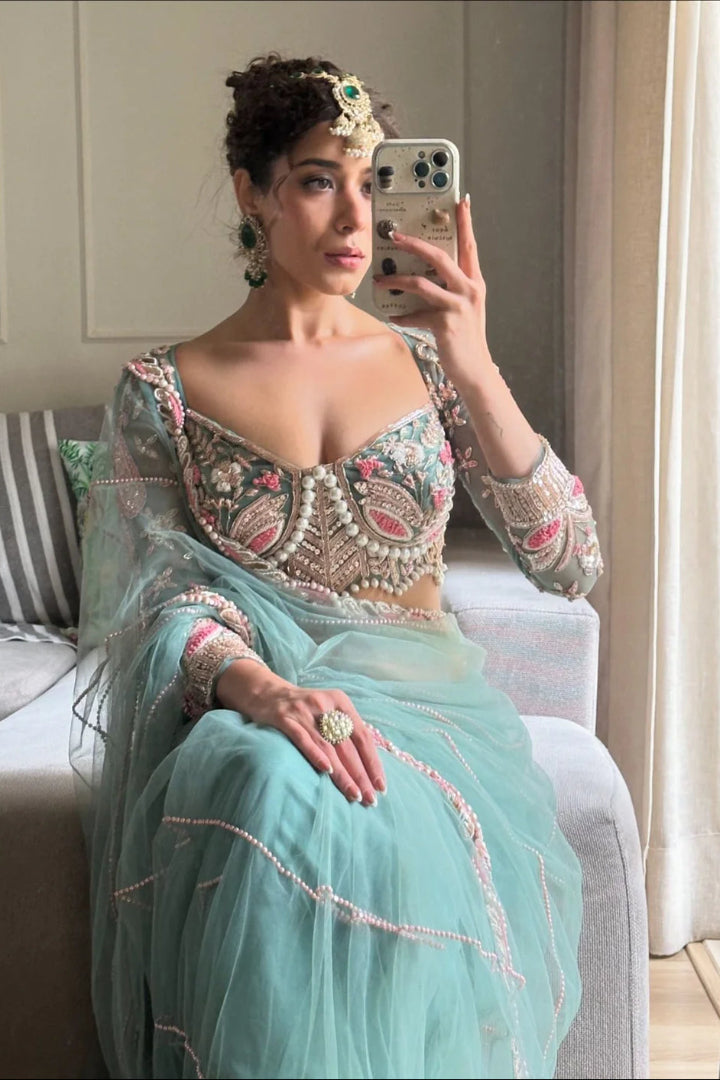 Woman in a traditional outfit taking a mirror selfie in a room.