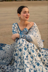 Woman in a blue and white floral dress sitting outdoors.