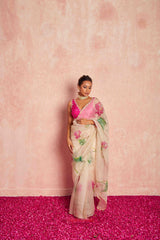 Woman wearing a floral saree with a pink blouse against a pink background