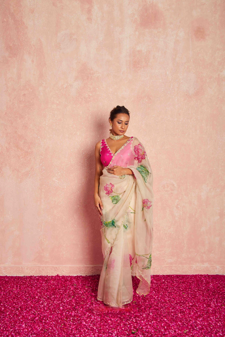Woman wearing a floral saree with a pink blouse against a pink background
