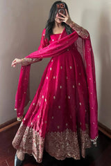 Person wearing a red traditional outfit with gold embroidery in a room.