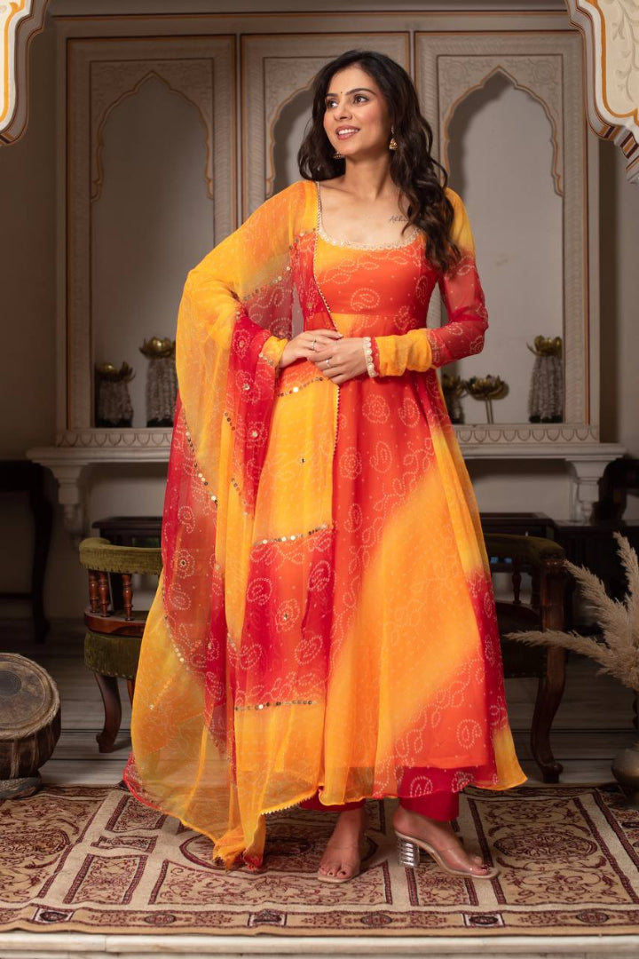 Woman in a traditional orange and yellow outfit standing in a decorated room.