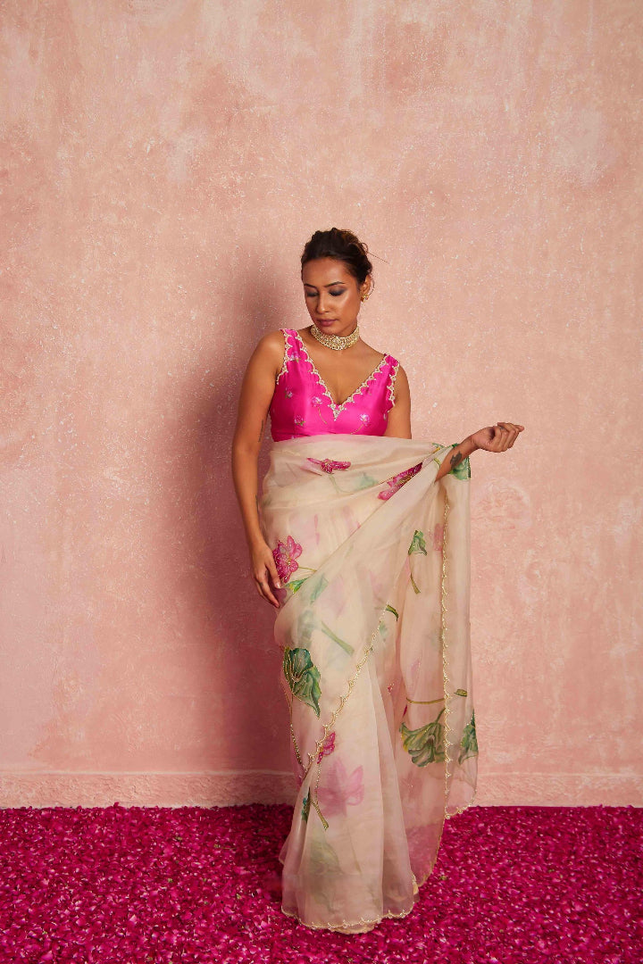 Woman wearing a pink blouse and floral saree against a pink background
