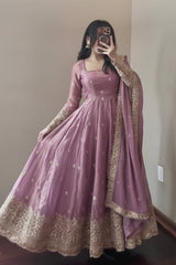 Person wearing a pink traditional outfit with gold embroidery in a room.
