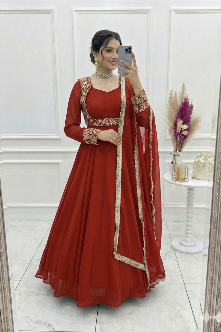 Woman in a red traditional outfit taking a mirror selfie in a white room.