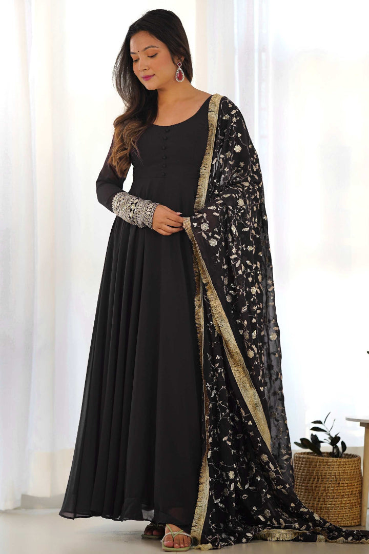 Woman wearing a black outfit with a floral dupatta in a bright room.