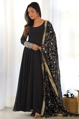 Woman wearing a black outfit with a floral dupatta in a bright room.
