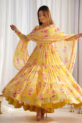 Woman wearing a yellow floral dress with a matching dupatta in a well-lit room.