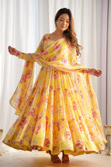 Woman wearing a yellow floral dress standing in front of white curtains.