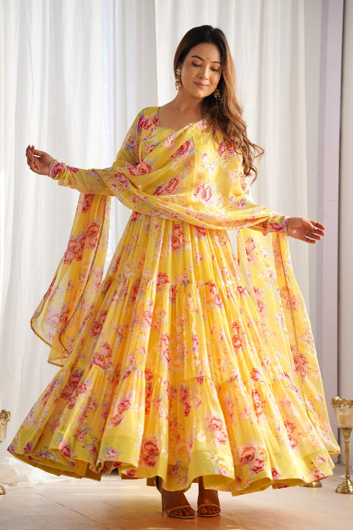 Woman wearing a yellow floral dress standing in front of white curtains.