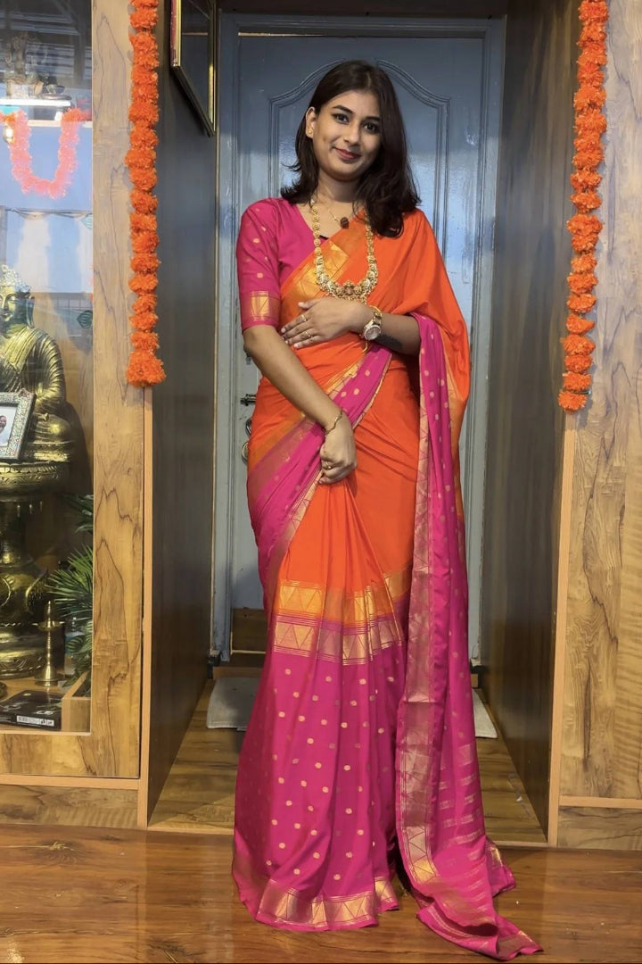 Woman in an orange and pink Zip & Go Gown saree standing in a doorway with decorative elements.
