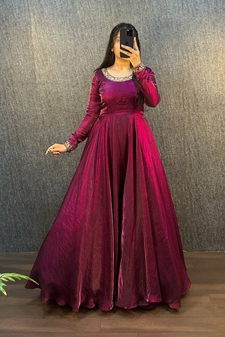 Person wearing a long burgundy dress against a textured wall.