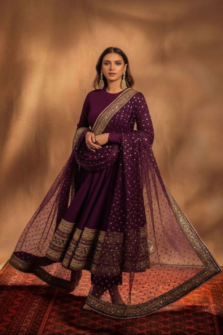 Woman in a traditional purple outfit with gold accents against a warm brown background