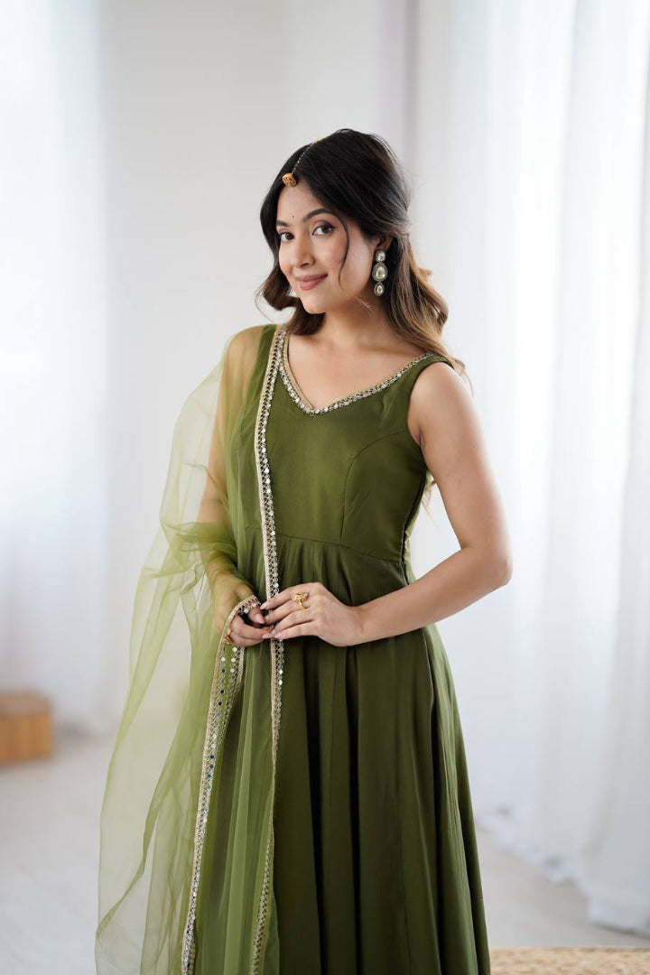 Woman wearing a green dress with a sheer overlay in a bright room