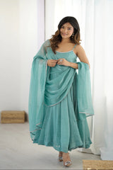 Woman wearing a light blue saree with a matching blouse in a minimalistic room.